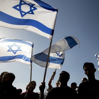Des manifestants israëliens brandissent le drapeau du pays. [Jack Guez]