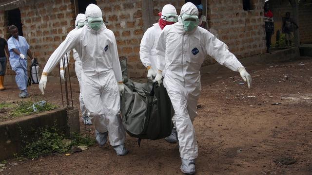 Des infirmiers déplacent un corps d'une personne victime du virus Ebola au Libéria. [EPA/Keystone - Ahmed Jallanzo]