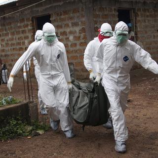 Des infirmiers déplacent un corps d'une personne victime du virus Ebola au Libéria. [EPA/Keystone - Ahmed Jallanzo]