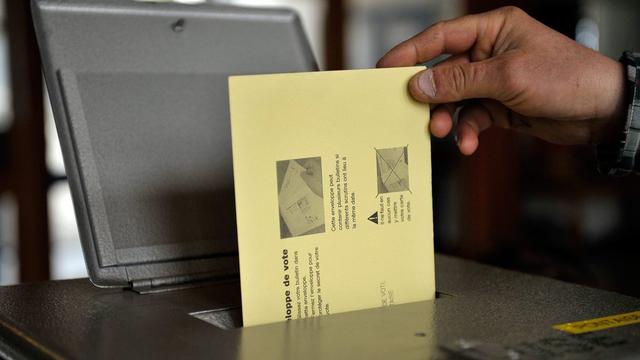 Un citoyen suisse dépose son bulletin de vote dans l'urne. [Dominic Favre]