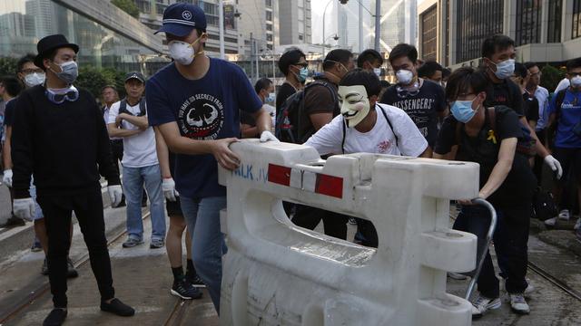 Des manifestants déplacent les barricades érigées par la police à Hong Kong. [Kin Cheung]
