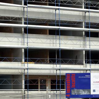 Devant un chantier un panneau annonce la mise en location de 4 immeubles locatifs pour la fin de l'année, à Genève. Image d'archives. [Salvatore Di Nolfi]