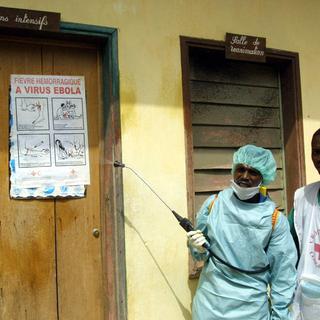 Des travailleurs de la Croix-Rouge désinfectant une salle de soins intensifs. [Desirey Minkoh]