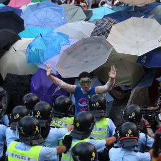 Certains manifestant utilisent des parapluies pour se prémunir des tirs de gaz lacrymogène des forces de l'ordre. [Aaron Tam]