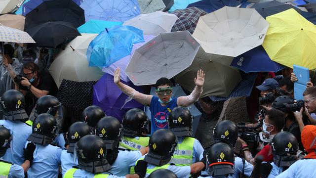 Certains manifestant utilisent des parapluies pour se prémunir des tirs de gaz lacrymogène des forces de l'ordre. [Aaron Tam]