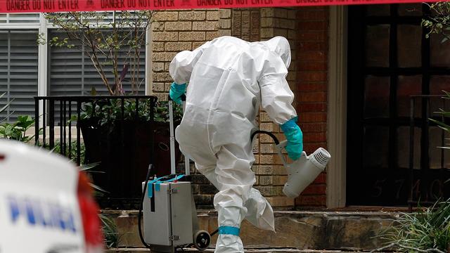 Un homme vêtu de vêtements de protection "traite" son pied après le traitement de la véranda d'un appartement à Dallas au Texas où une personne atteinte par le virus Ebola y réside, le 12 octobre 2014. [Mike Stone]