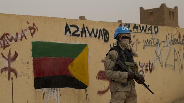 A Kidal, au Mali, un casque bleu de l'ONU devant un drapeau séparatiste de la région de Azawad.