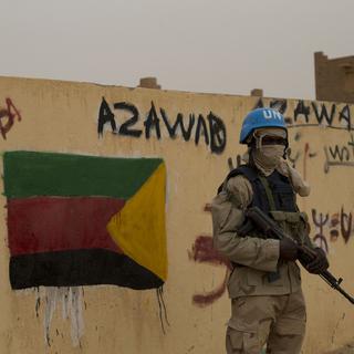 A Kidal, au Mali, un casque bleu de l'ONU devant un drapeau séparatiste de la région de Azawad.