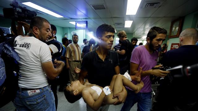 Un enfant blessé dans l'école de l'ONU est emmené vers l'hôpital. [AP Photo/Lefteris Pitarakis]