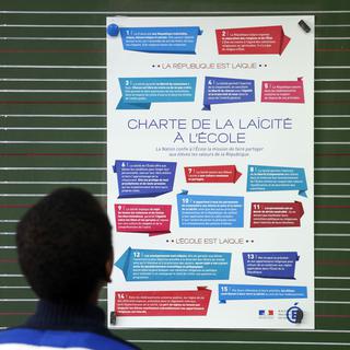Un élève regarde la charte de la laïcité à l'école, lors de la "Journée de la laïcité" le 9 décembre 2014. [AFP - Patrick Kovarik]