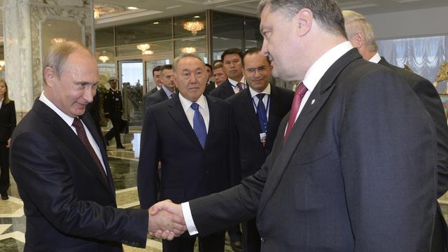 Le président russe Vladimir Poutine (à g.) et son homologue ukrainien Petro Porochenko se serrant la main le 26 août au sommet de Minsk, en Biélorussie. [Sergei Bondarenko]