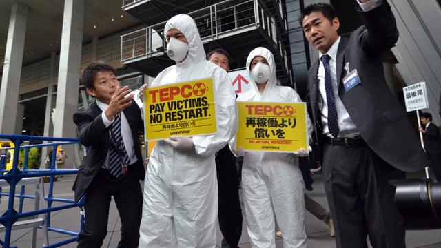 Des militants environnementaux japonais tentent de perturber une réunion des dirigeants de Tepco, en juin 2014 à Tokyo. [Yoshikazu TSUNO]