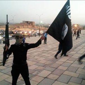 Un combattant du groupe Etat islamique (EI) brandit son fusil et le drapeau de l'EI.