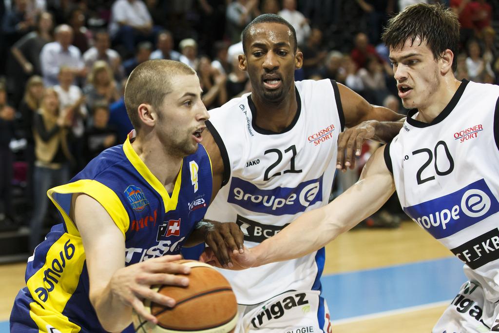 Le joueur de Union Neuchatel Brian Savoy, gauche, affronte les joueurs de Fribourg Olympic Edwin Draughan, centre, et Arnaud Cotture, droite, lors du 2e match des demi-finale playoff du championnat suisse de LNA de basketball entre Fribourg Olympic et Union Neuchatel Basket, ce mercredi 23 avril 2014 a la salle Saint-Leonard de Fribourg. (KEYSTONE/Salvatore Di Nolfi) [KEYSTONE - Di Nolfi]