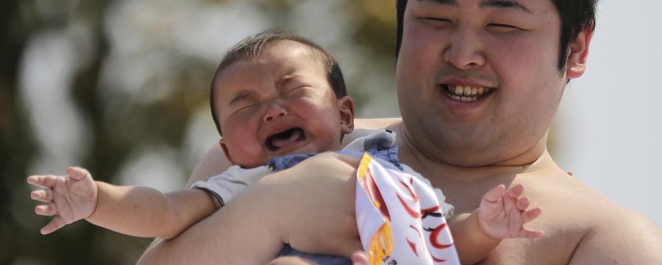 Samedi 26 avril: un sumo tient un bébé qui a participé à un concours de cris de bébés dans le temps de Senso-Ji à Tokyo, une cérémonie rituelle de prières pour qu'ils grandissent sans être malades. [AP Photo/Eugene Hoshiko]