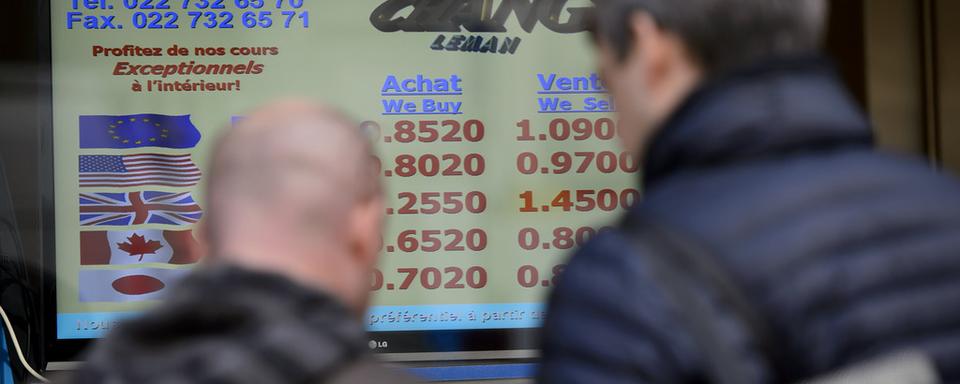 Des personnes devant un bureau de change jeudi à Genève. [Keystone - Martial Trezzini]