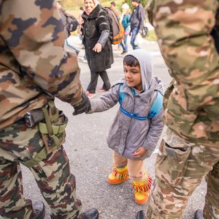 Des soldats slovènes tendent la main à un garçon, près de la frontière avec l'Autriche, le 25 octobre 2015. [AFP - Rene Gomolj]
