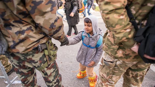 Des soldats slovènes tendent la main à un garçon, près de la frontière avec l'Autriche, le 25 octobre 2015. [AFP - Rene Gomolj]