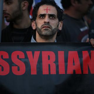 Un Assyrien brandis une bannière. [AP Photo/Keystone - Hussein Malla]