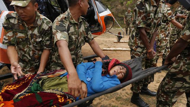 Une victime du séisme secourue par des soldats népalais. [AP Photo/Keystone - Wally Santana]