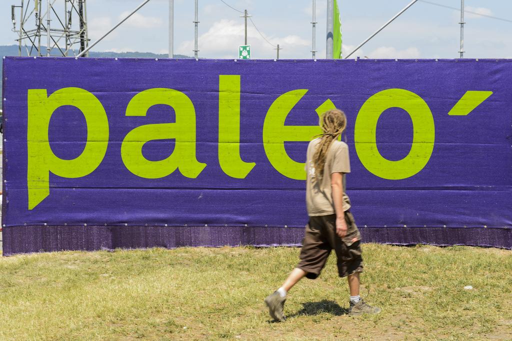 Un festivalier devant le logo de Paléo. [KEYSTONE - Jean-Christophe Bott]