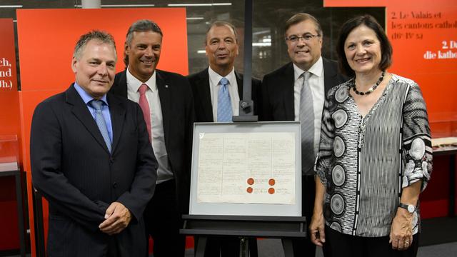 Les membres du Conseil d'Etat valaisan - Jacques Melly, Oskar Freysinger, Maurice Tornay, Jean-Michel Cina et Esther Waeber-Kalbermatten (de g. à d.) - posent mercredi à côté de la version originale de l'Acte de réunion du Valais à la Confédération en 1815.