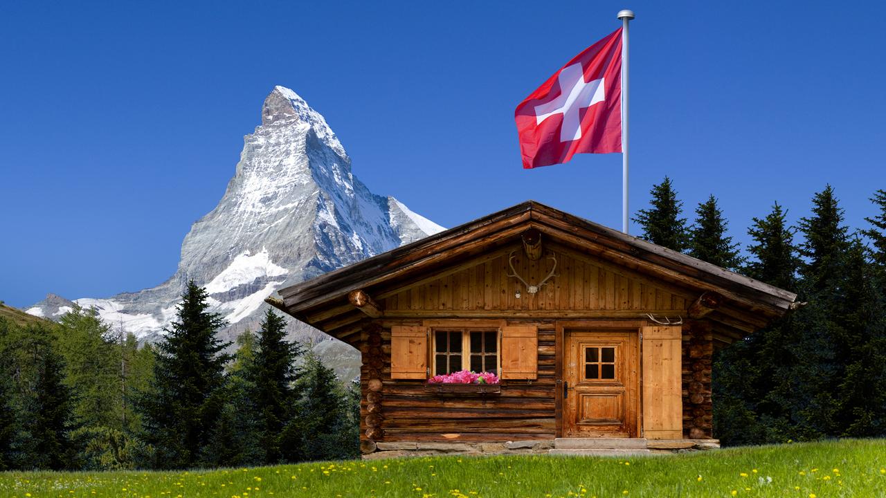 Un drapeau suisse flottant sur un chalet au pied du Cervin. C'est une des nombreuses représentations possibles de la Suisse. [Fotolia - by-studio]