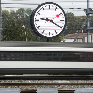 Un train passe devant l'horloge géante installée devant le quartier général des CFF à Berne. [KEYSTONE - CHRISTIAN BEUTLER]