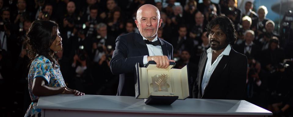 Jacques Audiard a reçu la Palme d'or à Cannes pour son film "Dheepan". Il pose avec les acteurs sri lankais Kalieaswari Srinivasan (à gauche) et Jesuthasan Antonythasan. [AFP - Bertrand Langlois]