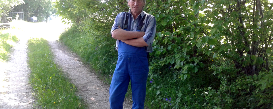 Fernand Cuche sur un chemin pierreux, sol valorisé par la Confédération au titre de la durabilité et de la protection du paysage. [RTS - Simon Corthay]