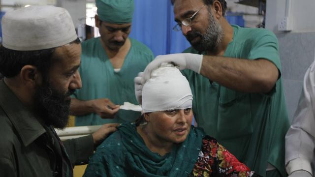 A Peshawar, des médecins pakistanais soignent une femme blessée par le séisme de lundi. [Keystone/AP Photo - Mohammad Sajjad]