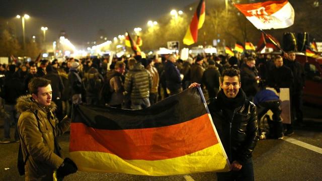 Des manifestants Pegida brandissent un drapeau allemand lors d'un rassemblement à Berlin, le 19 janvier 2015. [Anadolu Agency - Mehmet Kaman]