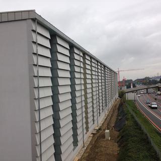 Ce bâtiment locatif au bord de l'A9 au Mont-sur-Lausanne est un modèle unique en Suisse. Sa façade nord constitue un mur anti-bruit. [RTS - Céline Fontannaz]
