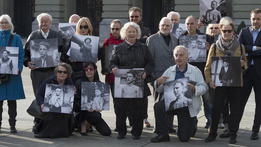 Des enfants placés posent avec une photo d'eux devant le Palais fédéral en mars 2014. [Keystone - Lukas Lehmann]