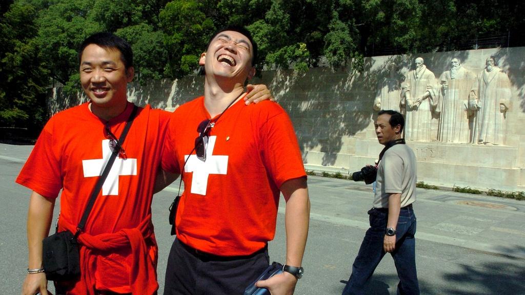 Des touristes chinois photographiés à Genève devant le Mur des Réformateurs. [Keystone - Martial Trezzini]
