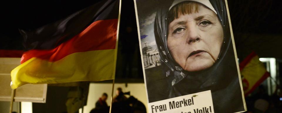 LA manifestation de Pegida du 12 janvier dernier à Dresde, avec une image d'Angela Merkel portnat le foulard. [AP Photo/Jens Meyer]