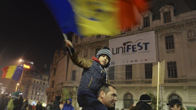 Un jeune protestataire brandit un drapeau roumain pendant les marches de protestation, Bucarest 8 novembre 2015. [NurPhoto / AFP - Artur Widak]