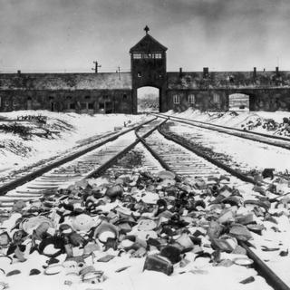 Photo prise en janvier 1945 montrant la grille d'entrée, que les prisonniers surnommaient "porte de la mort", et les rails du camp de concentration d'Auschwitz après sa libération par les troupes soviétiques. [Musée de l'Holocauste - © Reuters Photographer / Reuter]