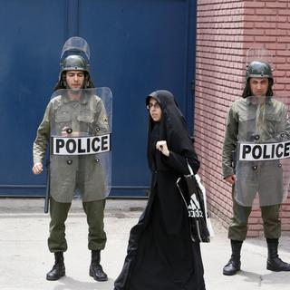 Une femme passe devant des policiers anti-émeutes à Téhéran.