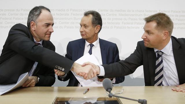 De gauche à droite, Christophe Darbellay, Philipp Müller et Toni Brunner concluent leur conférence de presse commune sur une poignée de mains, ce vendredi 27 mars 2015 à Berne. [Keystone - Peter Klaunzer]