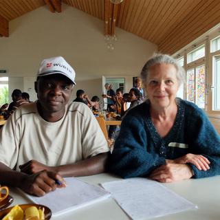 Camus Mboutene, requérant camerounais, et Barbara Baumgartner, bénévole de Riggisberg au Café Arc-en-ciel organisé tous les mardis par la paroisse. [RTS - Alain Arnaud]
