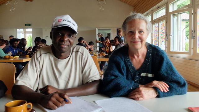 Camus Mboutene, requérant camerounais, et Barbara Baumgartner, bénévole de Riggisberg au Café Arc-en-ciel organisé tous les mardis par la paroisse. [RTS - Alain Arnaud]