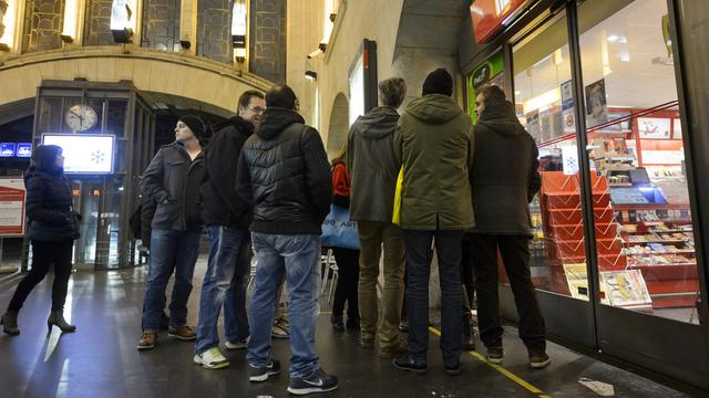 Des clients attendaient impatiemment l'ouverture d'un kiosque à la gare de Lausanne jeudi pour acheter leur copie de Charlie Hebdo. [Keystone - Laurent Gillieron]