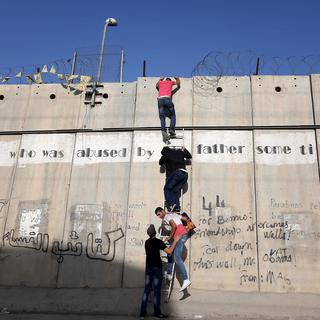 Jeunes Palestiniens tentant de passer par-dessus le mur qui sépare Jérusalem, le 19 juin 2015. [Anadolu Agency / AFP - Issam Rimawi]