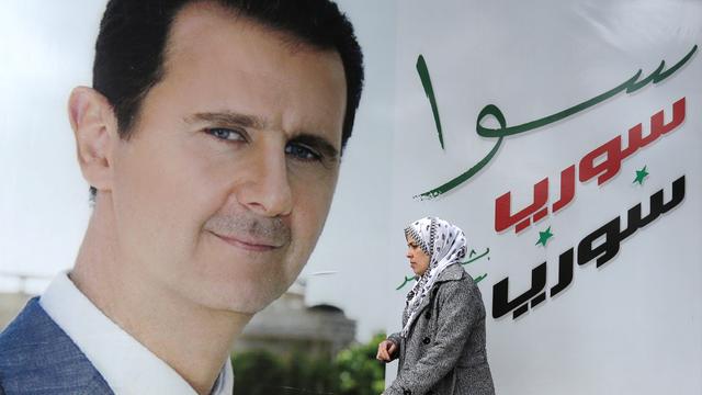 Une passante devant une afficher de Bachar al-Assad, à Damas. [Louai Beshara]