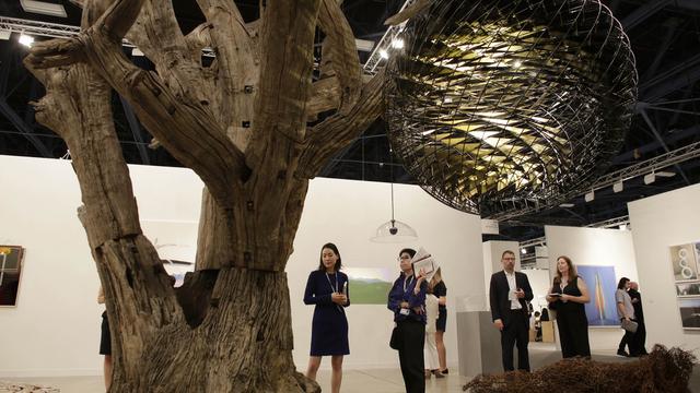 Un arbre sculpté par l'artiste-activiste chinois Ai Weiwei et un globe réalisé par Olafur Eliasson à la Galerie Neugerriemschneider, durant Art Basel Miami. [Lynne Sladky - AP Photo]