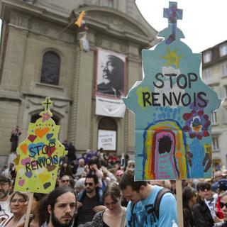 Les manifestants devant l'église Saint-Laurent réclament l'arrêt des renvois de migrants. [Keystone - Epa/Jean-Christophe Bott]