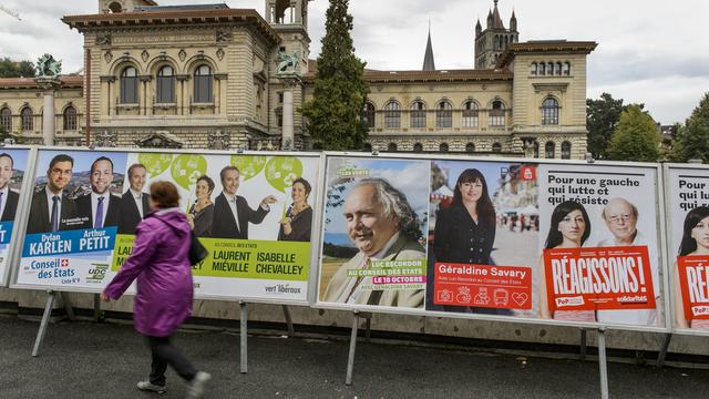 Une dame passe devant les affiches pour les élections fédérales à Lausanne. [Keystone - Jean-Christophe Bott]