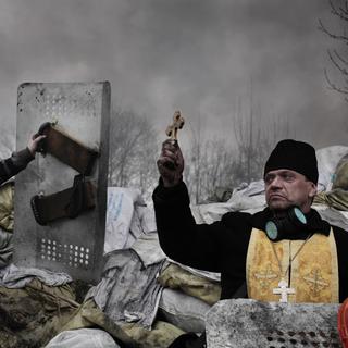 Un prêtre orthodoxe bénit des protestataire sur les barricades à Kiev, en Ukraine, le 20 février 2014. [DR - JEROME SESSINI]