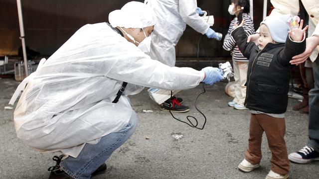 13 mars 2011, Koriyama (Japon). Un homme vérifie le taux de radiation de l'enfant qui quitte la zone d'évacuation décrétée après les accidents survenus aux centrales nucléaires de Fukushima. Cette catastrophe a été provoquée par un séisme de magnitude 9 et un tsunami, qui ont fait à eux deux près de 18'000 morts et disparus. [Kim Kyung-Hoon]